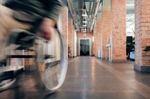 Čovek brzo prolazi kroz hodnik gurajući invalidska kolica